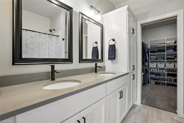 927 Summit Ct, Tiffin, IA 52340 - bathroom with double vanity, a spacious closet, and wood finished floors