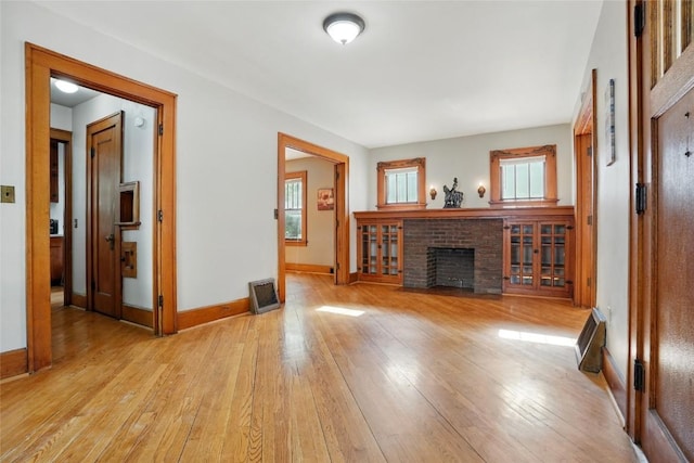 715 E Market St, Iowa City, IA 52245 - unfurnished living room featuring a fireplace, light wood-style floors, and baseboards