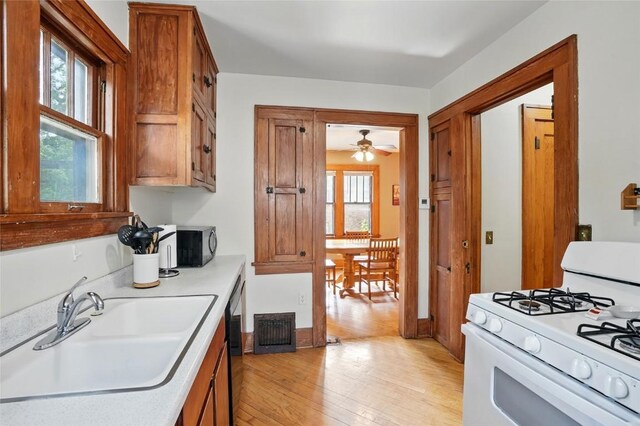 715 E Market St, Iowa City, IA 52245 - kitchen featuring white gas stove, a sink, light wood-type flooring, and brown cabinetry