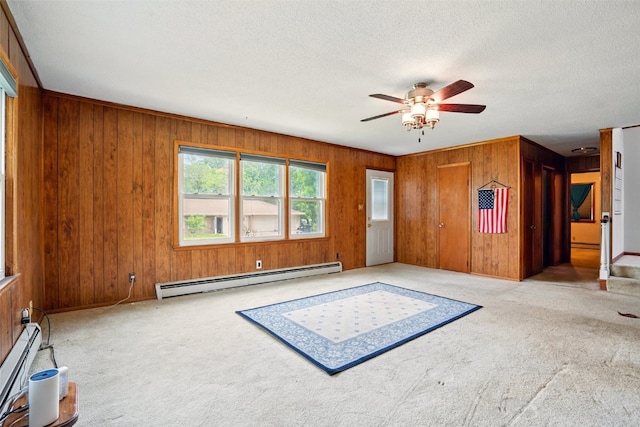 113 Chaffee Dr, Hiawatha, IA 52233 - unfurnished room featuring a baseboard heating unit, wooden walls, a baseboard radiator, ceiling fan, and carpet floors