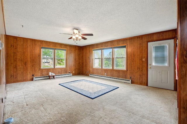 113 Chaffee Dr, Hiawatha, IA 52233 - empty room featuring a baseboard radiator, healthy amount of natural light, a ceiling fan, carpet floors, and wooden walls