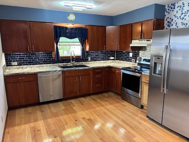 113 Chaffee Dr, Hiawatha, IA 52233 - kitchen with appliances with stainless steel finishes, under cabinet range hood, a sink, light wood finished floors, and backsplash