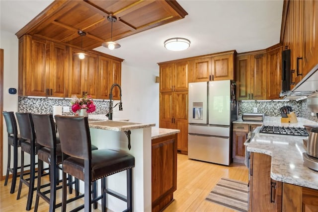 2545 F52 Trl, Parnell, IA 52325 - kitchen featuring stainless steel fridge, brown cabinetry, tasteful backsplash, a kitchen breakfast bar, and light wood-style flooring