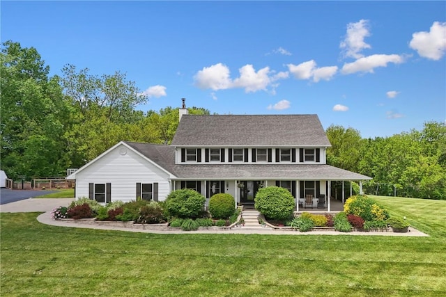 2545 F52 Trl, Parnell, IA 52325 - view of front facade with covered porch, a front yard, a chimney, and a shingled roof