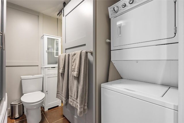 905 3rd St SE Unit 508, Cedar Rapids, IA 52401 - washroom with stacked washer / drying machine, dark tile patterned flooring, and a barn door
