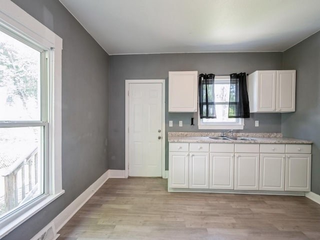 280 14th Ave SW, Cedar Rapids, IA 52404 - kitchen with a sink, white cabinets, light wood finished floors, and baseboards