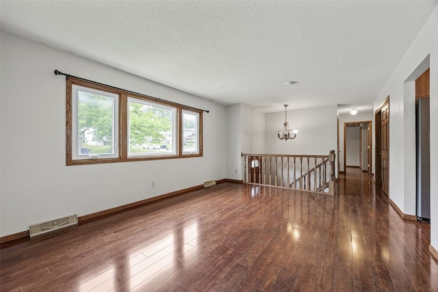 2536 N Ave NW, Cedar Rapids, IA 52405 - empty room with a chandelier, wood finished floors, a textured ceiling, and baseboards