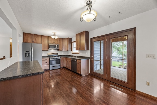 2536 N Ave NW, Cedar Rapids, IA 52405 - kitchen featuring appliances with stainless steel finishes, dark countertops, healthy amount of natural light, dark wood-type flooring, and a textured ceiling