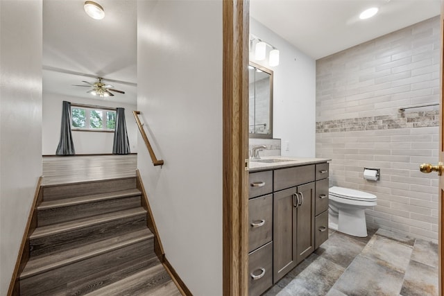 2536 N Ave NW, Cedar Rapids, IA 52405 - stairs featuring a ceiling fan, tile walls, and baseboards