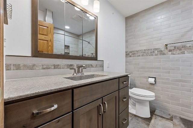 2536 N Ave NW, Cedar Rapids, IA 52405 - bathroom featuring tile walls, vanity, tiled shower, toilet, and stone finish floors