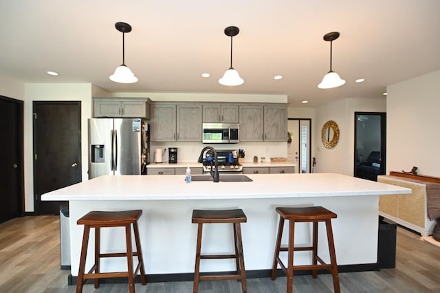 3902 Bluebird Dr SW, Cedar Rapids, IA 52404 - kitchen featuring stainless steel appliances, a sink, an island with sink, wood finished floors, and light countertops