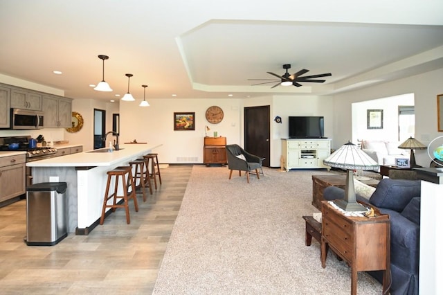 3902 Bluebird Dr SW, Cedar Rapids, IA 52404 - living room featuring a tray ceiling, a ceiling fan, recessed lighting, and light wood-style floors