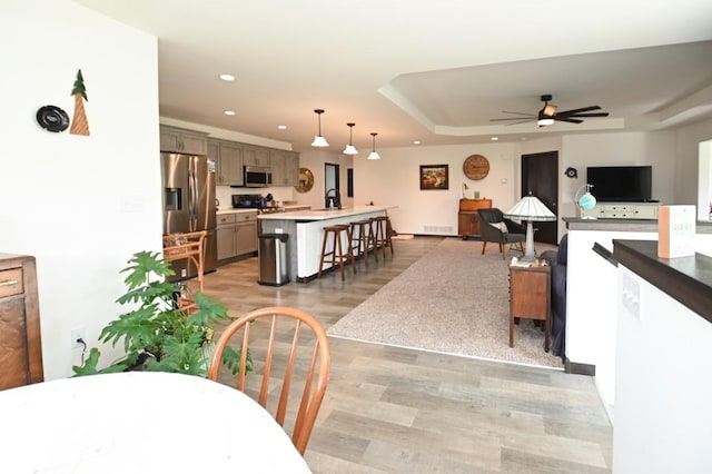 3902 Bluebird Dr SW, Cedar Rapids, IA 52404 - dining area with light wood-style flooring, recessed lighting, a raised ceiling, and ceiling fan