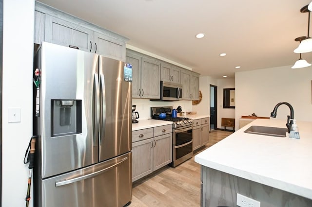 3902 Bluebird Dr SW, Cedar Rapids, IA 52404 - kitchen featuring stainless steel appliances, a sink, light wood-style floors, light countertops, and hanging light fixtures