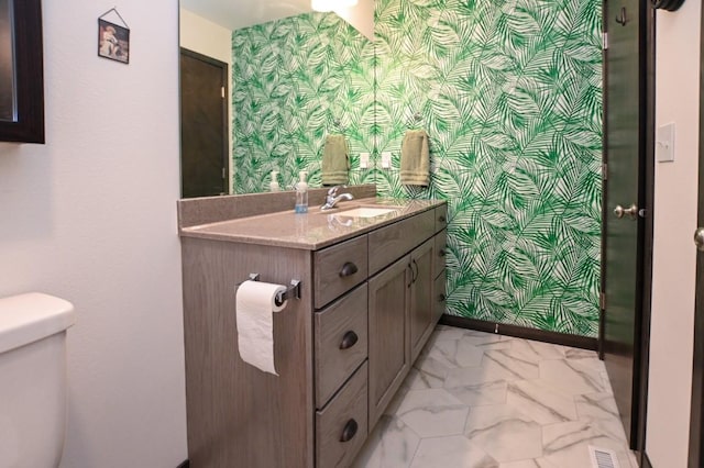 3902 Bluebird Dr SW, Cedar Rapids, IA 52404 - bathroom with wallpapered walls, vanity, toilet, and baseboards