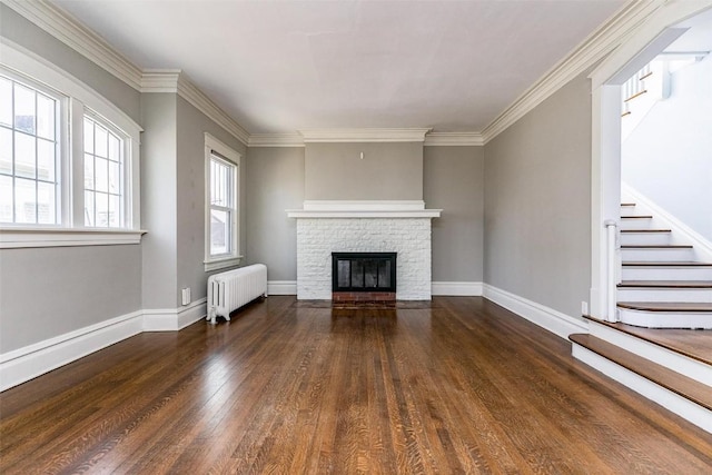 384 21st St SE, Cedar Rapids, IA 52403 - unfurnished living room with radiator, wood finished floors, stairs, a stone fireplace, and ornamental molding