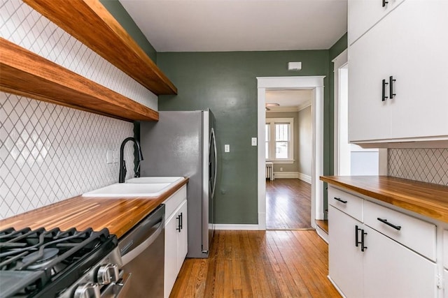 384 21st St SE, Cedar Rapids, IA 52403 - kitchen featuring wooden counters, open shelves, a sink, appliances with stainless steel finishes, and decorative backsplash