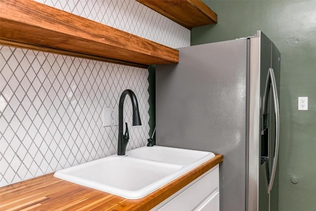 384 21st St SE, Cedar Rapids, IA 52403 - kitchen view of a sink, stainless steel refrigerator with ice dispenser, white cabinets, butcher block counters, and open shelves