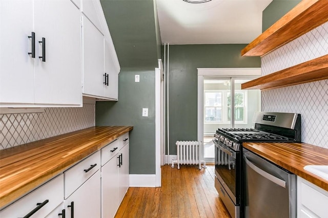 384 21st St SE, Cedar Rapids, IA 52403 - kitchen featuring radiator heating unit, butcher block counters, stainless steel appliances, light wood finished floors, and white cabinets