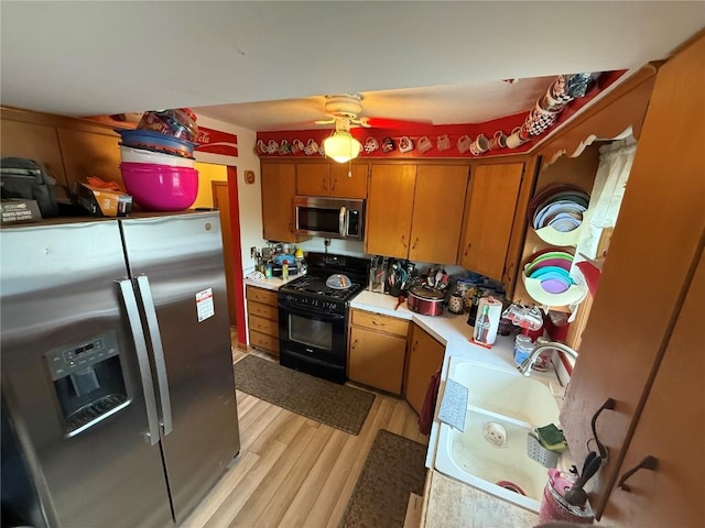 101 26th Avenue Dr SW, Cedar Rapids, IA 52404 - kitchen with appliances with stainless steel finishes, light countertops, light wood finished floors, brown cabinetry, and a ceiling fan