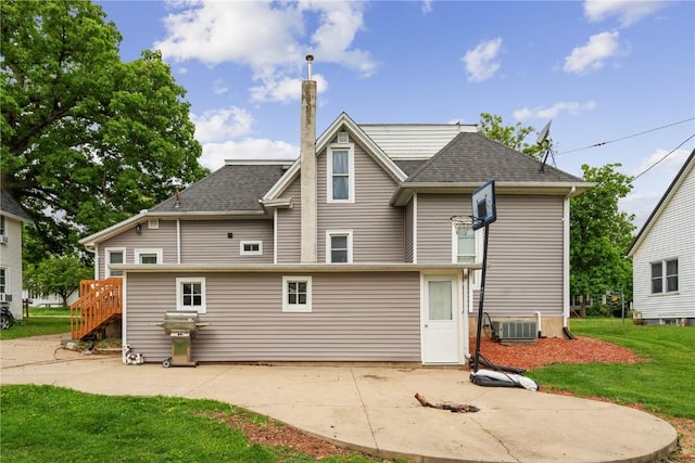 311 3rd St S, Coggon, IA 52218 - rear view of house with a patio area, a lawn, roof with shingles, and central air condition unit