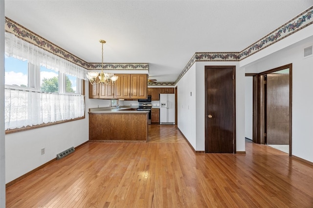 1083 Rainbow Blvd, Hiawatha, IA 52233 - kitchen with stainless steel electric stove, white refrigerator with ice dispenser, a chandelier, a peninsula, and a sink