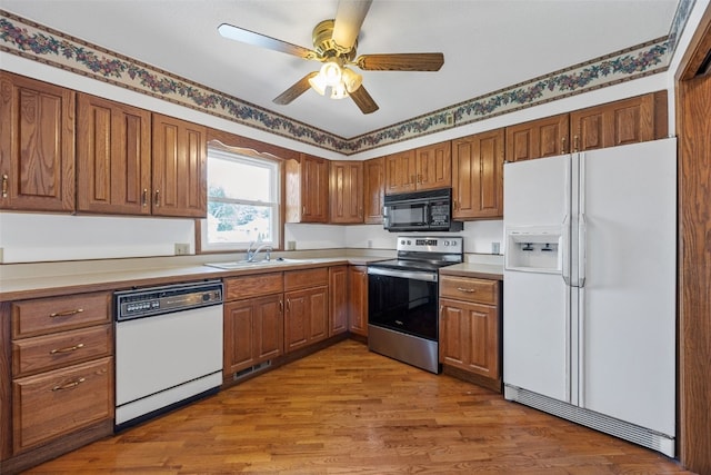 1083 Rainbow Blvd, Hiawatha, IA 52233 - kitchen featuring white appliances, a sink, brown cabinets, wood finished floors, and a ceiling fan