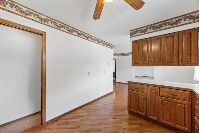 1083 Rainbow Blvd, Hiawatha, IA 52233 - kitchen with wood finished floors, a ceiling fan, brown cabinets, light countertops, and baseboards