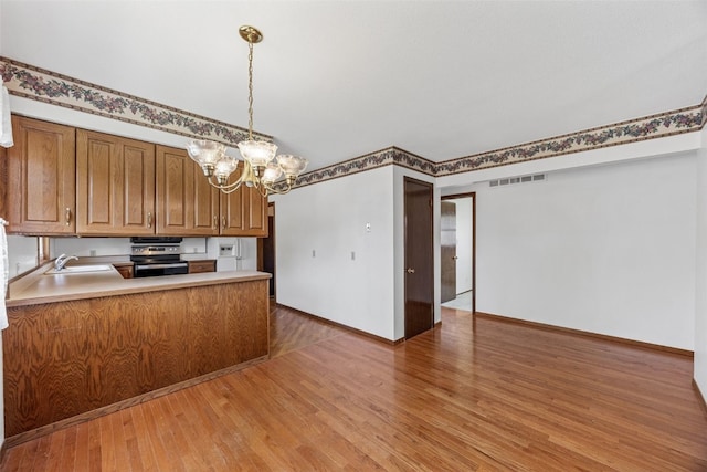 1083 Rainbow Blvd, Hiawatha, IA 52233 - kitchen featuring a chandelier, light wood-style floors, brown cabinetry, a sink, and pendant lighting