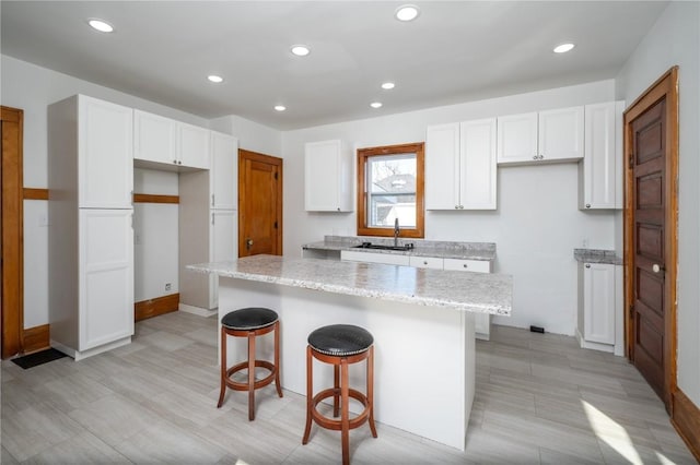 2253 73rd St, Van Horne, IA 52346 - kitchen featuring a kitchen island, white cabinetry, a kitchen bar, recessed lighting, and light stone counters