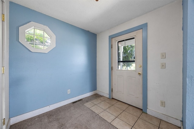 87 14th Ave SW, Cedar Rapids, IA 52404 - doorway to outside featuring healthy amount of natural light, baseboards, a textured ceiling, and light tile patterned floors