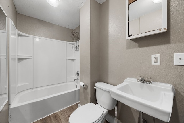 87 14th Ave SW, Cedar Rapids, IA 52404 - bathroom featuring wood finished floors, toilet, shower / bathtub combination, a textured wall, and a sink