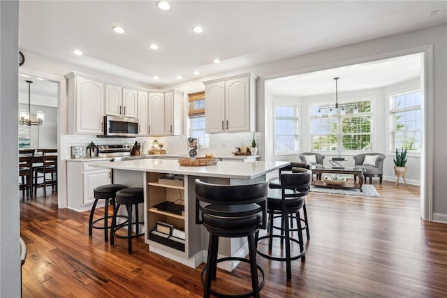 2545 Silver Oak Trl, Marion, IA 52302 - kitchen featuring appliances with stainless steel finishes, a chandelier, a breakfast bar, light countertops, and tasteful backsplash
