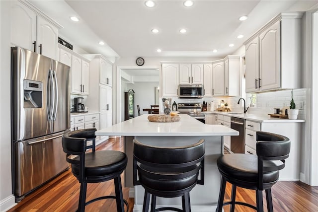 2545 Silver Oak Trl, Marion, IA 52302 - kitchen with appliances with stainless steel finishes, a kitchen bar, recessed lighting, dark wood-style flooring, and a center island