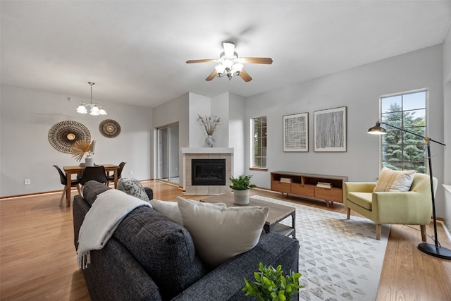 364 Camden Rd, Iowa City, IA 52245 - living area featuring ceiling fan, light wood-style flooring, a chandelier, a tiled fireplace, and baseboards