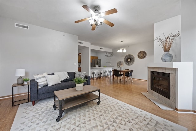 364 Camden Rd, Iowa City, IA 52245 - living room with a ceiling fan, light wood-style flooring, a tiled fireplace, and baseboards