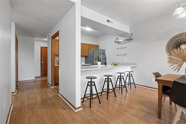 364 Camden Rd, Iowa City, IA 52245 - kitchen featuring stainless steel fridge with ice dispenser, light wood-style flooring, a breakfast bar, light countertops, and baseboards