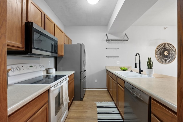 364 Camden Rd, Iowa City, IA 52245 - kitchen featuring appliances with stainless steel finishes, a sink, light wood-style flooring, light countertops, and brown cabinetry