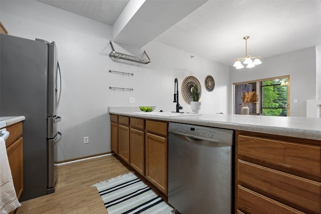 364 Camden Rd, Iowa City, IA 52245 - kitchen with stainless steel appliances, brown cabinets, a sink, light wood-style flooring, and a chandelier