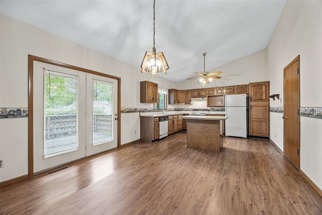 1042 Arthur Dr NW, Cedar Rapids, IA 52405 - kitchen featuring white appliances, wood finished floors, vaulted ceiling, a kitchen island, and pendant lighting