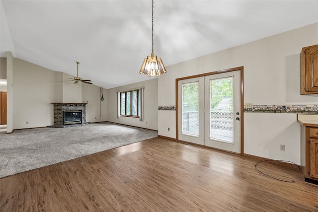1042 Arthur Dr NW, Cedar Rapids, IA 52405 - unfurnished living room featuring wood finished floors, a brick fireplace, ceiling fan, vaulted ceiling, and a chandelier