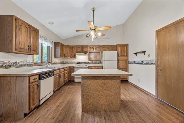 1042 Arthur Dr NW, Cedar Rapids, IA 52405 - kitchen with vaulted ceiling, white appliances, light wood finished floors, a kitchen island, and brown cabinets