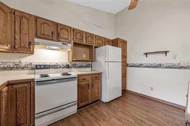 1042 Arthur Dr NW, Cedar Rapids, IA 52405 - kitchen with white appliances, under cabinet range hood, light countertops, wood finished floors, and brown cabinetry