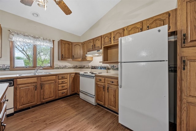1042 Arthur Dr NW, Cedar Rapids, IA 52405 - kitchen featuring white appliances, vaulted ceiling, brown cabinetry, a ceiling fan, and under cabinet range hood