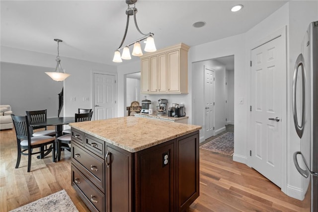 4000 Majestic Ct NE, Cedar Rapids, IA 52411 - kitchen with cream cabinetry, freestanding refrigerator, light wood finished floors, dark brown cabinetry, and pendant lighting