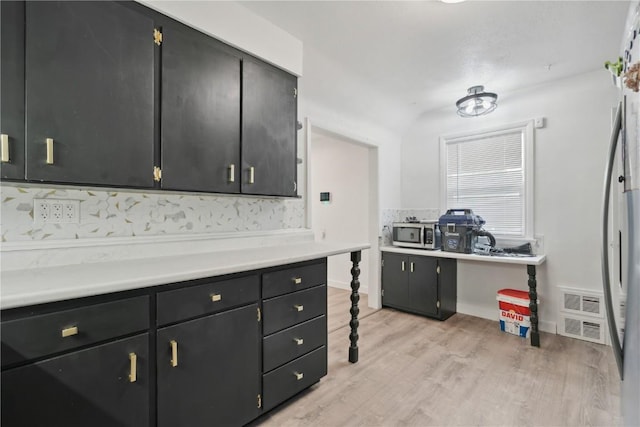 654 34th St SE, Cedar Rapids, IA 52403 - kitchen featuring stainless steel appliances, dark cabinets, light wood-style floors, and light countertops