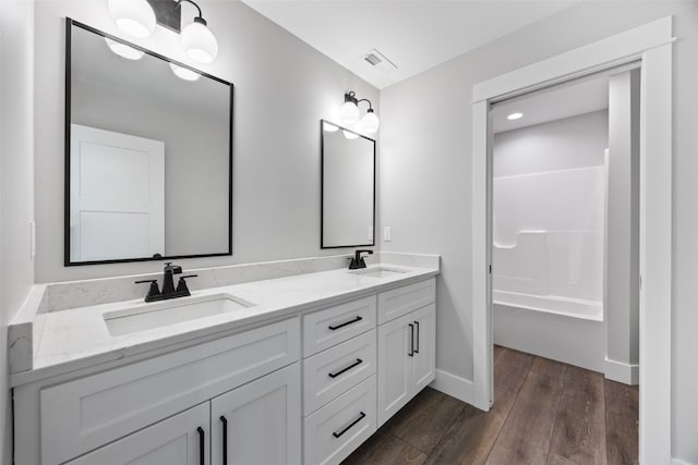 1504 Legend Dr, Tiffin, IA 52340 - full bathroom with double vanity, wood finished floors, baseboards, and  shower combination