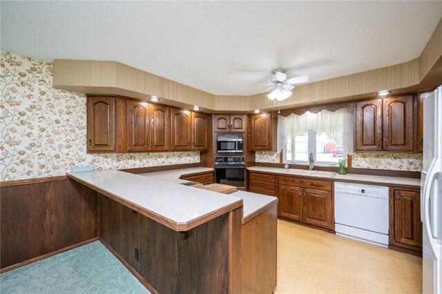 409 Oak St, Rowley, IA 52329 - kitchen featuring white dishwasher, stainless steel microwave, oven, wallpapered walls, and a sink