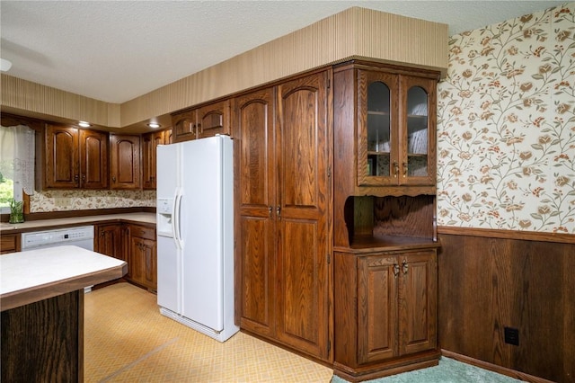 409 Oak St, Rowley, IA 52329 - kitchen with white appliances, wallpapered walls, glass insert cabinets, a textured ceiling, and light countertops