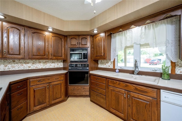 409 Oak St, Rowley, IA 52329 - kitchen with black oven, a sink, stainless steel microwave, wallpapered walls, and dishwasher